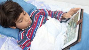 Ragazzino con fibrosi cistica consulta il tablet dal letto a casa propria